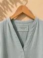 Close-up of the V-neck and embroidered label of the women's sage green long linen dress Rustrel